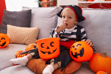Adorable caucasian boy wearing pirate costume eating sweet at home