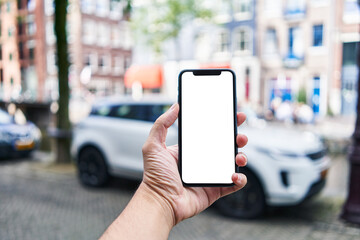 Man holding smartphone showing white blank screen at car parking