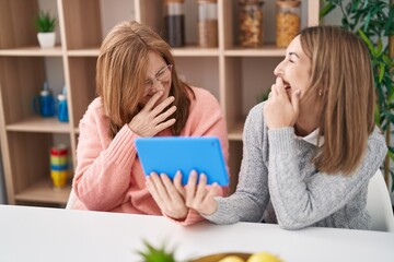 Mother and daughter using touchpad sitting on desk at home