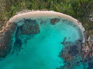 Aerial view of a pristine beach surrounded by lush green trees in a tranquil setting