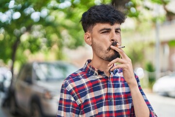 Young hispanic man smoking at street