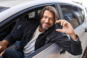 Middle age man smiling confident holding key of new car at street