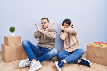 Young couple moving to a new home rejection expression crossing arms doing negative sign, angry face