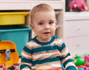 Adorable caucasian baby smiling confident sitting on floor at kindergarten