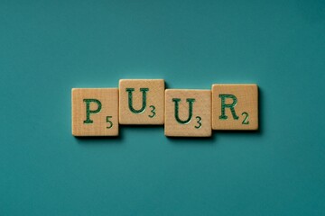 Wooden letters spelling the word "puur" (dutch for pure) on a blue background