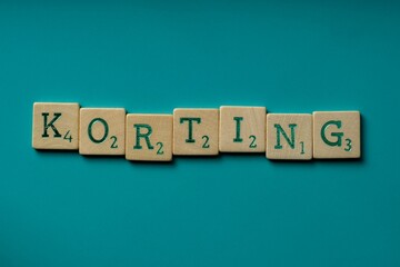 Wooden letters spelling the word "korting" (dutch for discount) on a blue background
