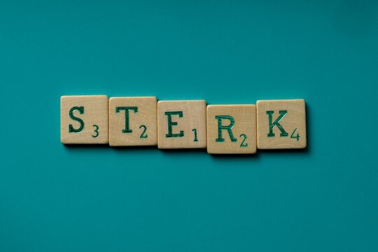 Wooden letters spelling the word "sterk" (dutch for strong) on a blue background.