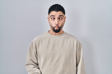 Young handsome man standing over isolated background making fish face with lips, crazy and comical gesture. funny expression.