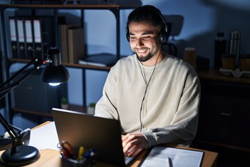 Young handsome man working using computer laptop at night with a happy and cool smile on face....