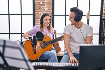 Man and woman musicians playing piano and spanish guitar at music studio
