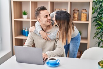 Man and woman couple hugging each other using laptop at home