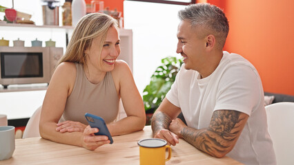 Man and woman couple using smartphone sitting on table at dinning room