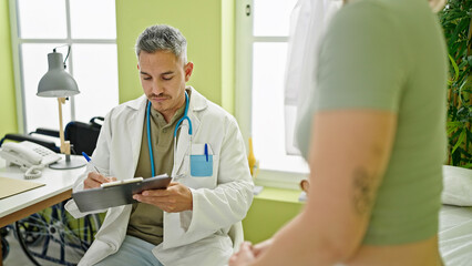 Obraz premium Man and woman doctor and patient having consultation writing medical report at the clinic