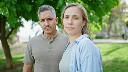 Obraz premium Man and woman couple standing together with serious face at park
