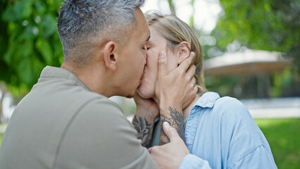 Man and woman couple standing together kissing at park