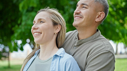 Obraz premium Man and woman couple hugging each other looking to the side at park