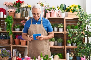 Middle age grey-haired man florist smiling confident using touchpad at florist