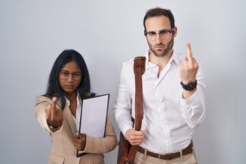 Interracial business couple wearing glasses showing middle finger, impolite and rude fuck off expression