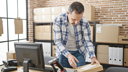 Middle age man ecommerce business worker using computer checking package at office