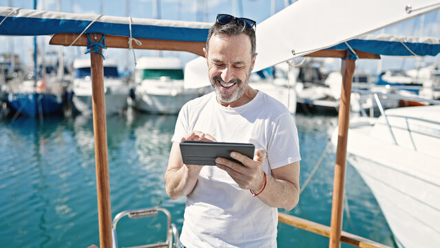 Middle age man smiling confident using touchpad at boat