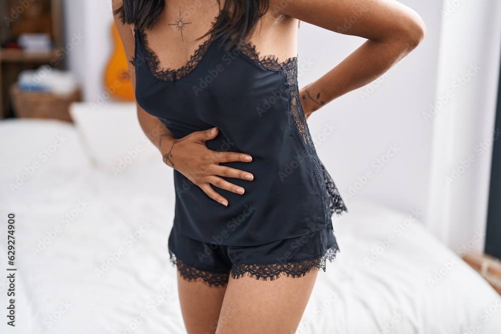 Poster Young hispanic woman suffering for menstrual pain at bedroom