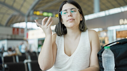 Young beautiful hispanic woman listening to voice message at the airport