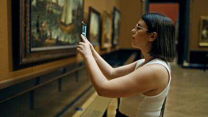 Young beautiful hispanic woman visiting art gallery taking pictures with smartphone at Art Museum in Vienna - obrazy, fototapety, plakaty