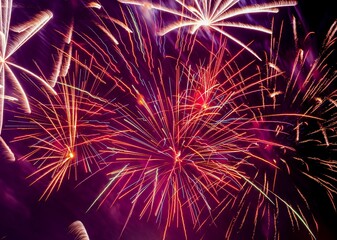 Abstract background - bright beams of festive colorful fireworks against black night sky.