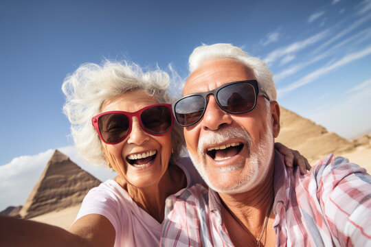 Happy elderly couple tourists take a selfie against the backdrop of the Egyptian pyramids. Travel retirement concept. AI generated.