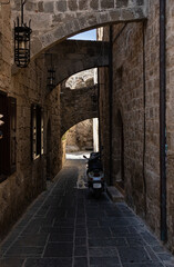 selective focus on a narrow stone street on the island of Rhodes with old lantern and modern motorcycle