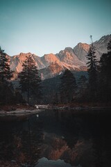 Vertical image of Lake Eibsee in Germany featuring a distant figure walking along the water's edge