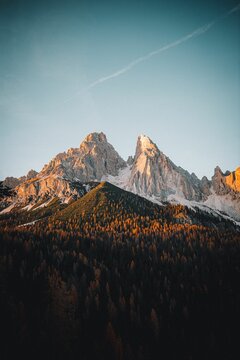 Stunning vertical shot of the majestic Dolomites mountains illuminated by the golden sunset light