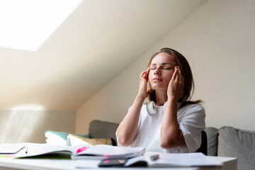 Female student doing homework and having a headache.