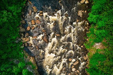 Aerial shot of the Malbale River surrounded by rocks and greenery in Quebec, Canada