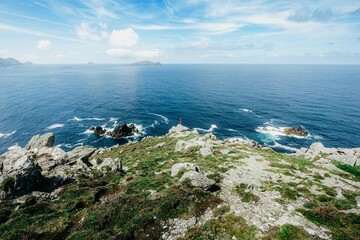 Man standing at the edge of shoreline looking into distance.