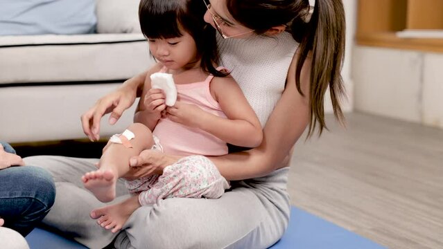 Asian mother take care adorable child hurt on knee with bandage, naughty kid getting wound fall while running, kid's medical insurance planning against sickness and accidents, healthcare lifestyle