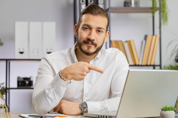 Business man working online on laptop, finishing work, positive feedback, like, approving application, good offer sale advertisement. Freelancer guy at office workplace looking at camera, talking