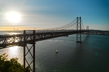 Fototapeta na wymiar Aerial shot of The 25 de Abril Bridge crossing Tagus River is a suspension bridge connecting the city of Lisbon and Almada. Sunny summer day. Portugal
