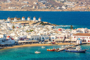 Chora port of Mykonos island with red church, famous windmills, ships and yachts during summer sunny day. Aegean sea, Greece - obrazy, fototapety, plakaty
