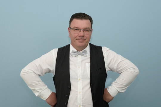 A man in a classic shirt, vest and bow tie. Portrait on a light background