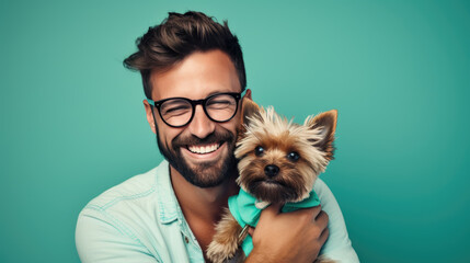 Young man holds a dog puppy in his arms on blue background.