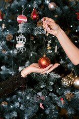 Hands of girls with New Year's toys close-up. The Christmas tree is decorated with beautiful toys.