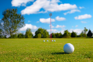 Close-up golf ball on tee with blur green bokeh background.