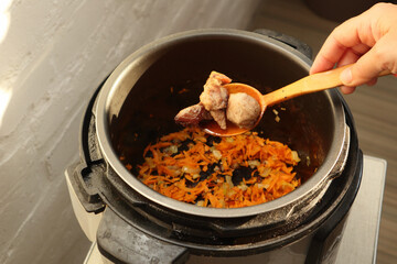 Woman using multi cooker in kitchen. Modern electric multi cooker.