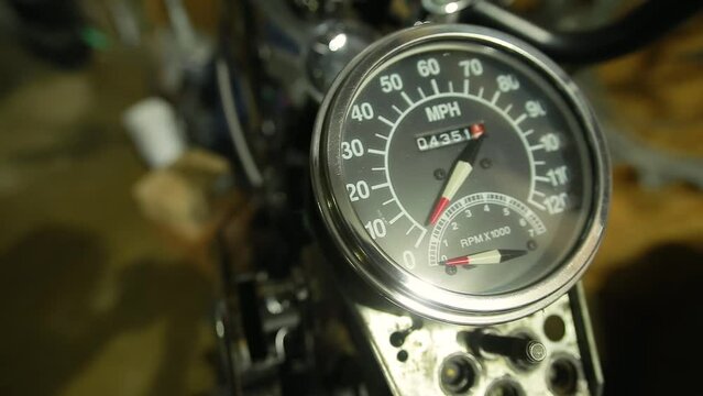 Close-up of speedometer with chrome bezel and odometer on a vintage motorcycle with shiny metal in a garage. Marking in miles per hour. Bike repair in the workshop
