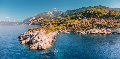 The aerial perspective provides a unique vantage point to appreciate the majestic collision of the rocky coastline and the relentless waves of the Aegean Sea. - obrazy, fototapety, plakaty