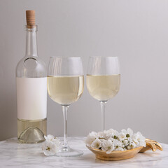 Elegant trendy, stylish stemmed glass with white wine on gray background with botlle. Summer art food drink concept. Mockup template	