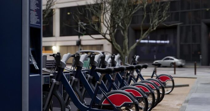 Row of Green bicycles for rent. Electric bicycle charging station. Shared electric bikes parked on city street early in the morning