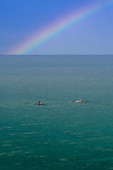 Obraz premium Wild or open water swimming in calm water under a rainbow with copy space