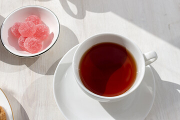 a cup of black tea fruit marmalade on a white wooden table. Morning tea, sunny good morning.